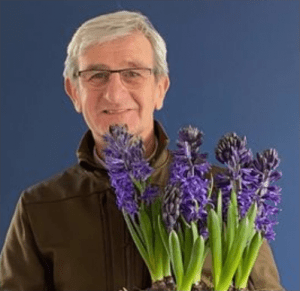 Alan Down of Down to Earth holding purple flowers on a blue background