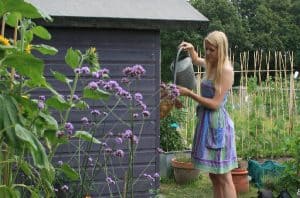 Katie of Lavender & Leeks watering plants next to a shed